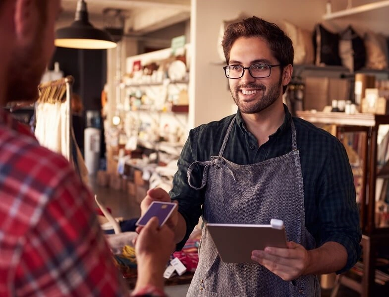 Man working in retail takes card from customer for payment.