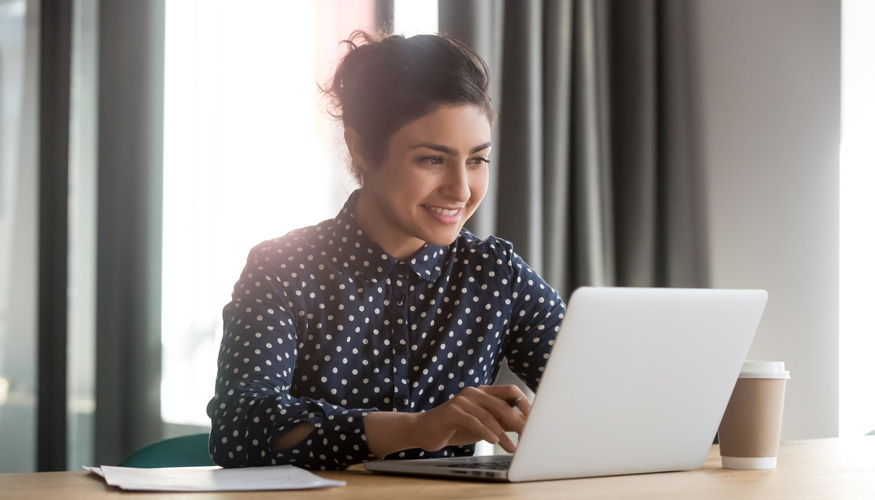 Happy young indian businesswoman using computer sit at office desk