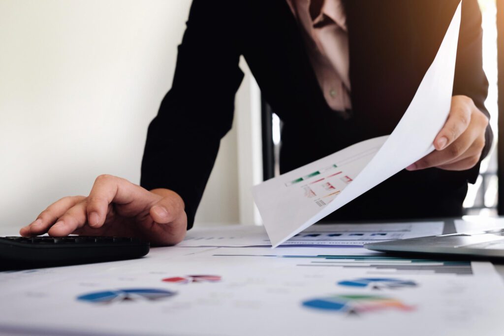 businessman working with calculator and digital tablet computer with financial business strategy layer effect in office, bookkeeper and auditor concept.