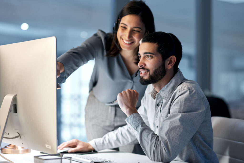 Business woman and business man explaining processes on the computer.