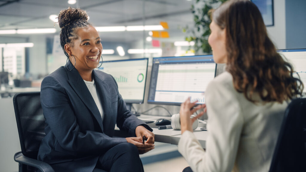 Two Female Colleagues Talk to Each Other.