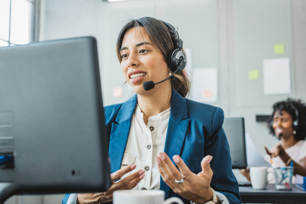 Friendly woman talking with costumers by headset.