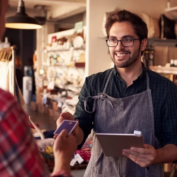 Man working in retail takes card from customer for payment.